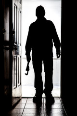 Intruder at door, in silhouette with pipe wrench