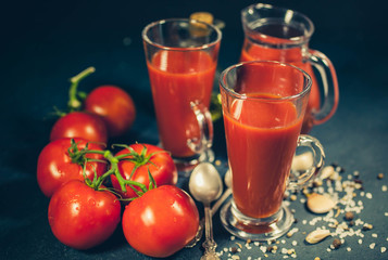 Red tomatoes, juice and spices on dark background. Tomato juice. Selective focus. Low-key lighting
