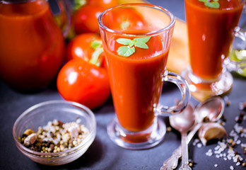 Red tomatoes, juice and spices on dark background. Tomato juice. Close up. Selective focus. Low-key lighting