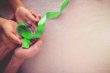 Adult and child hands holding Lime Green Ribbon,  family and children mental health awareness