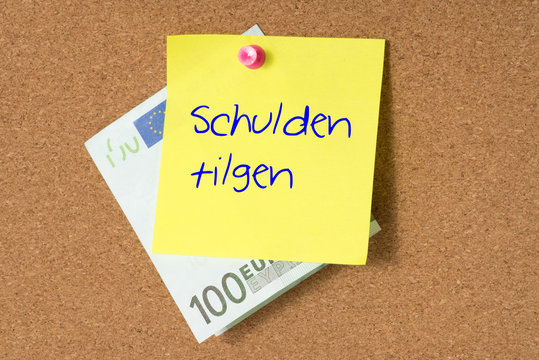 Euro Geldschein und ein Notiz mit dem Text Schulden tilgen