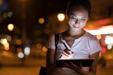 Woman sketching on digital tablet computer at outdoor in the evening