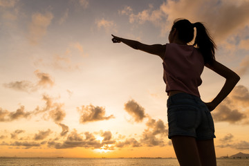 Silhouette of woman pointing with finger in sky
