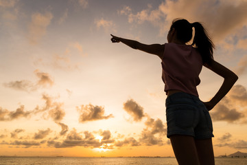 Fototapeta premium Silhouette of woman pointing with finger in sky