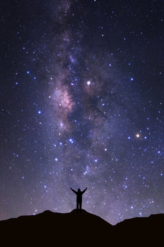Milky way galaxy with stars and space dust in the universeand and silhouette of a standing happy man