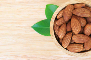 Almonds in wooden bowl on wood table background