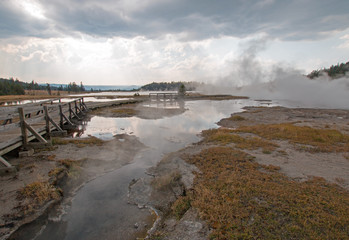 Elevated wooden boardwalk / walkway going past Black Warrior Springs and Tangled Creek and overlooking Hot Lake in the Lower Geyser Basin in Yellowstone National Park in Wyoming United States