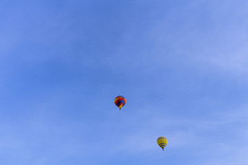 Two balloons flying over a blue sky
