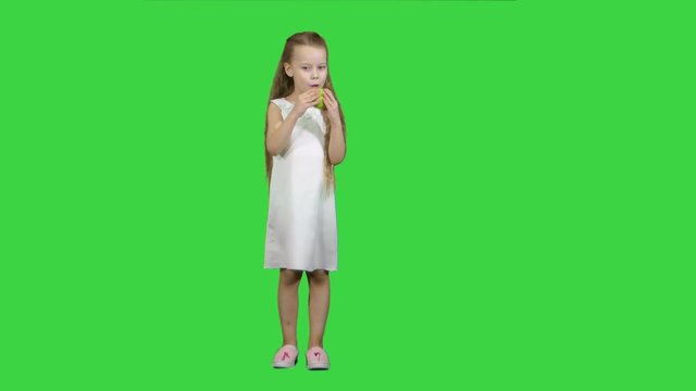 Little girl with green apple, eating it on a Green Screen, Chroma Key