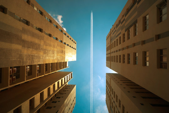 Airplane contrail against clear blue sky with abstract low angle view of common modern business skyscrapers.