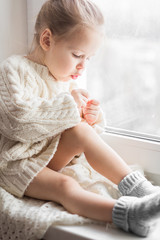 A little girl in the white knitted sweater - 167429561