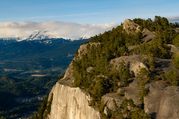 View point from cliff above valley with mountains and clouds.