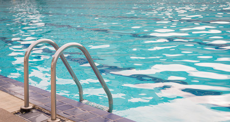 Grab bars ladder in the blue swimming pool