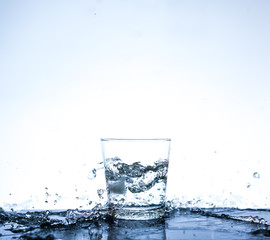 Water splashing in the glass with reflection on mirror.