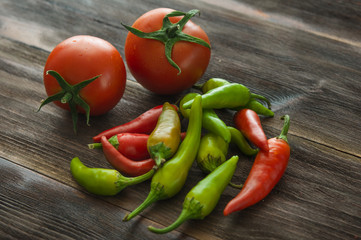 Ripe tomatoes, hot chili pepper on a wooden table