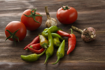 Ripe tomatoes, hot chili peppers, garlic on a wooden table
