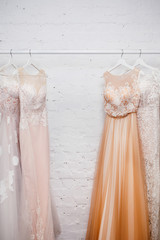 Copy space Wedding dresses for the bride on hangers against a white background of brick in the store. Concept wedding, engagement, attributes, clothing, love.