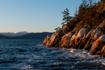 Ocean waves hitting rocks on coast while sunset