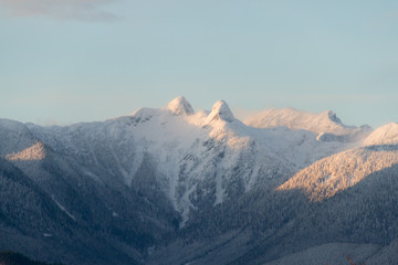 Fototapeta na wymiar Mountains in snow with orange light from sunrise or susnet