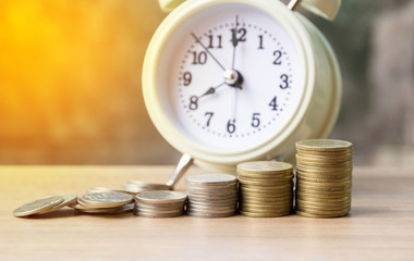 Stacking coins with wooden table and clock .Business Finance and time of money concept
