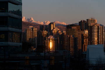 Winter cityscape with mountains and sunrise illuminating building