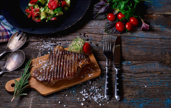 Beef steak. Piece of Grilled BBQ beef marinated in spices and herbs on a rustic wooden board over rough wooden desk with a copy space.