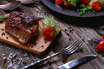 Overhead view of colorful vegetables, savory sauces and salt served with grilled steak on a rustic wooden counter in a country steakhouse.Close-up