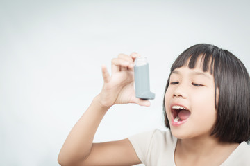 Little girl using Asthma inhaler for breathing.