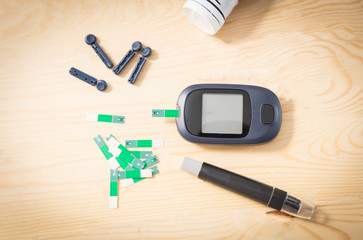 Glucometer set  with  Indicator Strips For Blood Glucose Testing  and Syringe for inject on the wooden table.