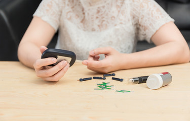 Close-up Of Woman's Hand Checking Blood Sugar Level With Glucometer at home.