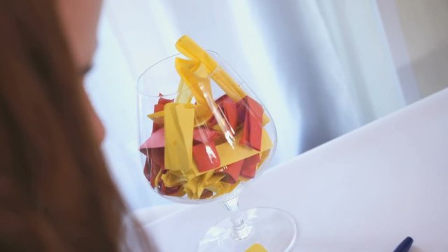 Wedding forfeits. Wedding event. Male hand putting a note in a large glass goblet. Close-up