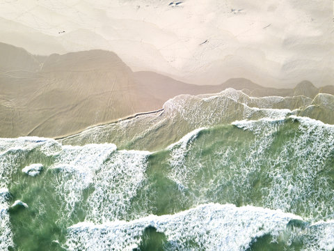 Aerial view over waves breaking onto the beach