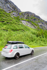 Car driving in rainy mountain landscape on wet road.