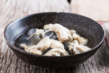 Opened Oysters on dark bowl on  wood background