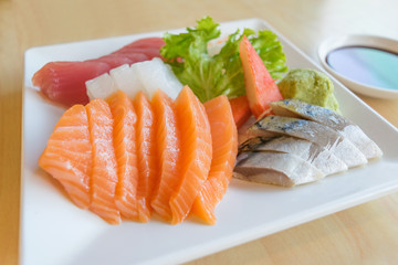 salmon and other fish raw with wasabi and sauce on table wood in