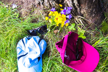 sunglasses, two caps and flowers on the ground composition