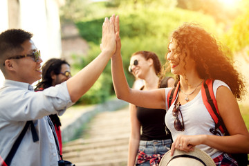 Happy tourist friends are giving a high five slapping each other's hand.