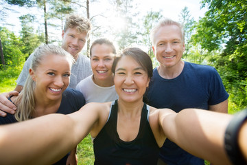 Happy Mature Woman Taking Selfie With Friends In Forest