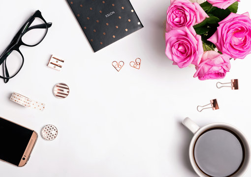 Pink roses, coffee and gold color accessories on the whit background.