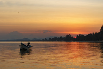 Orange sunset on the sea with a small boat, Thailand