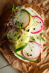 Sandwich with red radish, cucumber and fresh herbs and pepper. Top view.