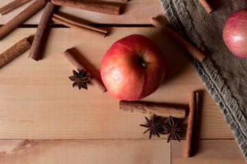Fresh ripe red apples and cinnamon sticks on wooden background.