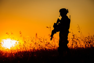 Fototapeta na wymiar Silhouette of military soldier with weapons at sunset. shot, holding gun, colorful sky. military concept.