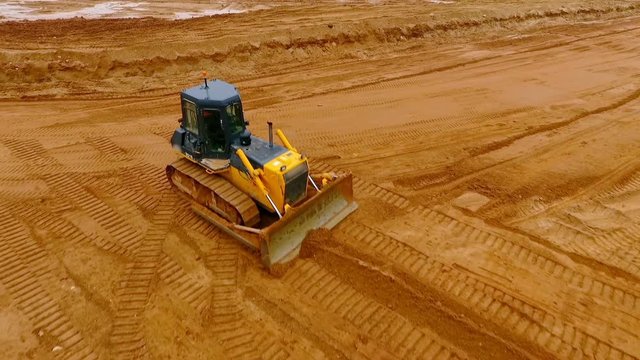 Mining machinery. Bulldozer machine. Aerial view of crawler bulldozer mining sand at quarry. Bulldozer at industrial area. Sky view of mining machinery working at sand quarry. Earth moving equipment