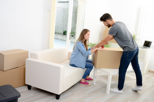 happy young couple student roommate packing boxes and moving furnitures during their move into new home flat apartment