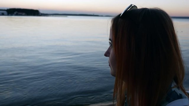 Red-haired girl enjoys nature and sunset at sea.