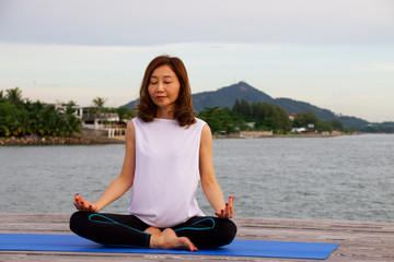 Woman is yoga and meditation at pier