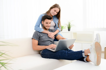 portrait of a young happy couple at home making project for future with laptop computer on internet