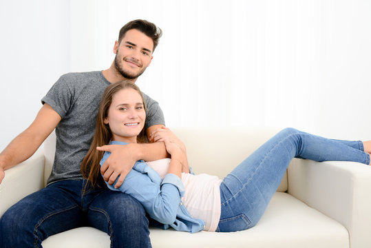 portrait of a young happy cheerful love couple at home together in sofa