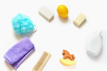 Flat lay bathroom set/  Purple terry towel, blue sponge puff, white soap, lemon fruit, white shampoo bottle, wooden comb and toy horse. Free space for text. Top view stock photo
